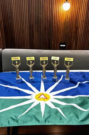 Cinco troféus do Startup Awards 2025 sobre a bandeira de Uberlândia